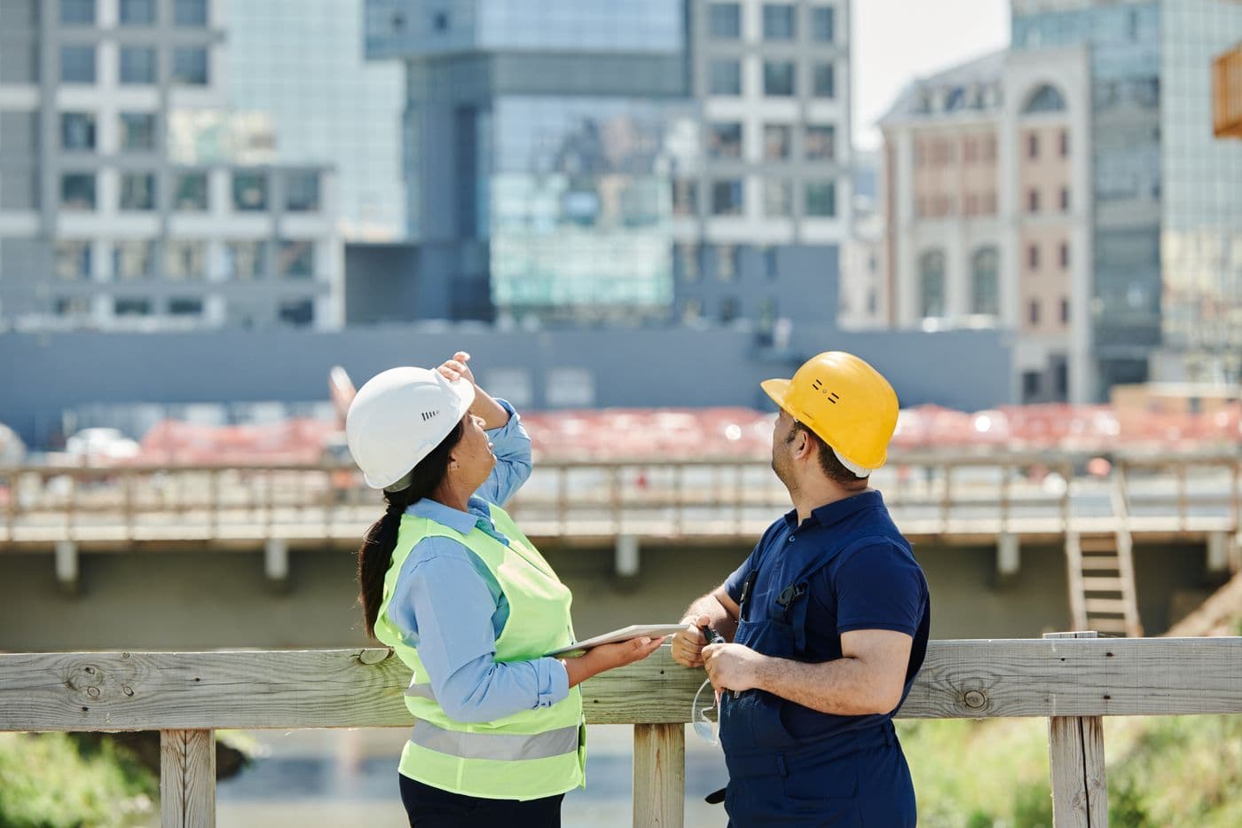 Dos trabajadores con casco revisando una instalación en la calle