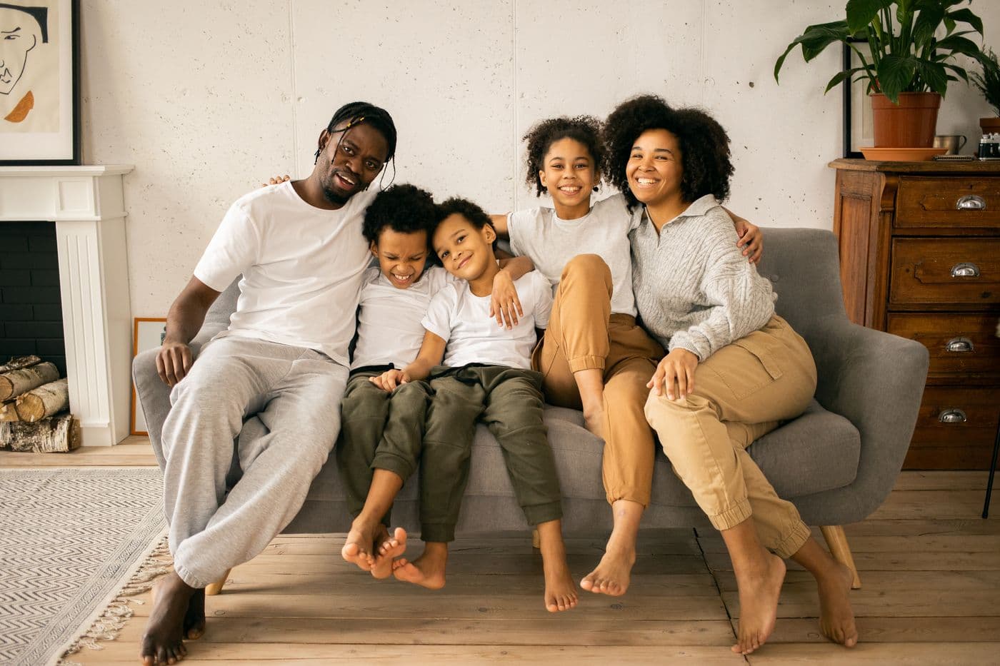 Una madre y sus dos hijos viendo televisión juntos en el sofá de su casa